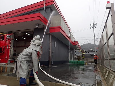 消防団からの援護注水を受け、２階へ進入する消防隊員